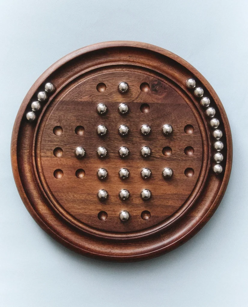 Gioco solitario Zara Home con base circolare in legno e pedine metalliche.