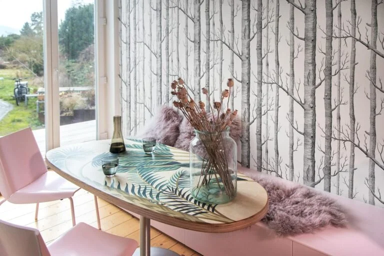 Zona pranzo del progetto Pink Kitchen con tavolo decorato e seduta rosa