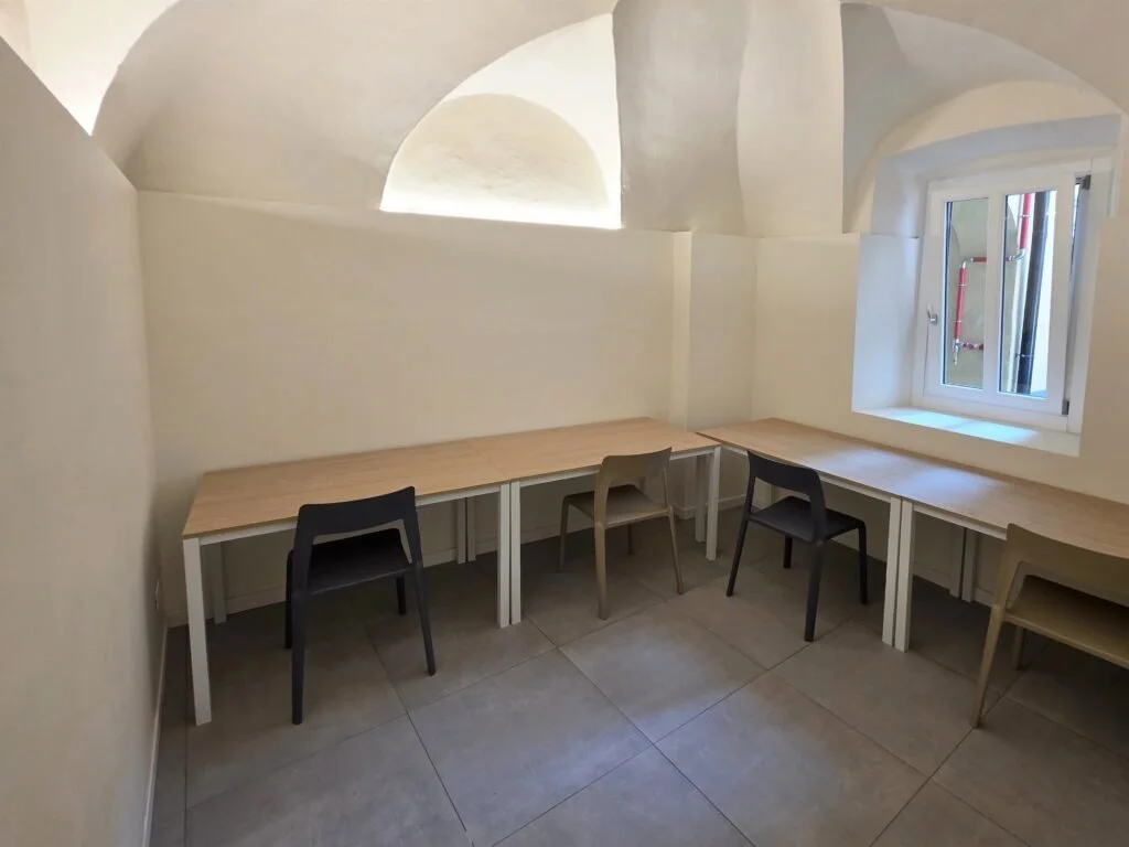 Area studio di The Yard con scrivanie chiare, volte e finestra in legno