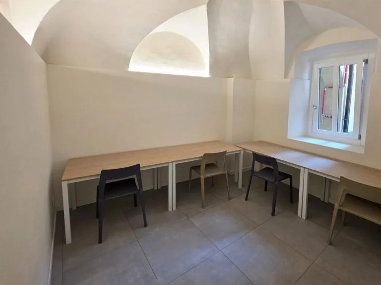 Area studio di The Yard con scrivanie chiare, volte e finestra in legno