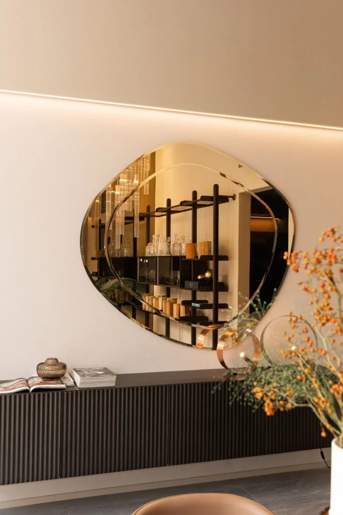 Specchio rotondo con cornice dorata sopra una madia nello store Riflessi