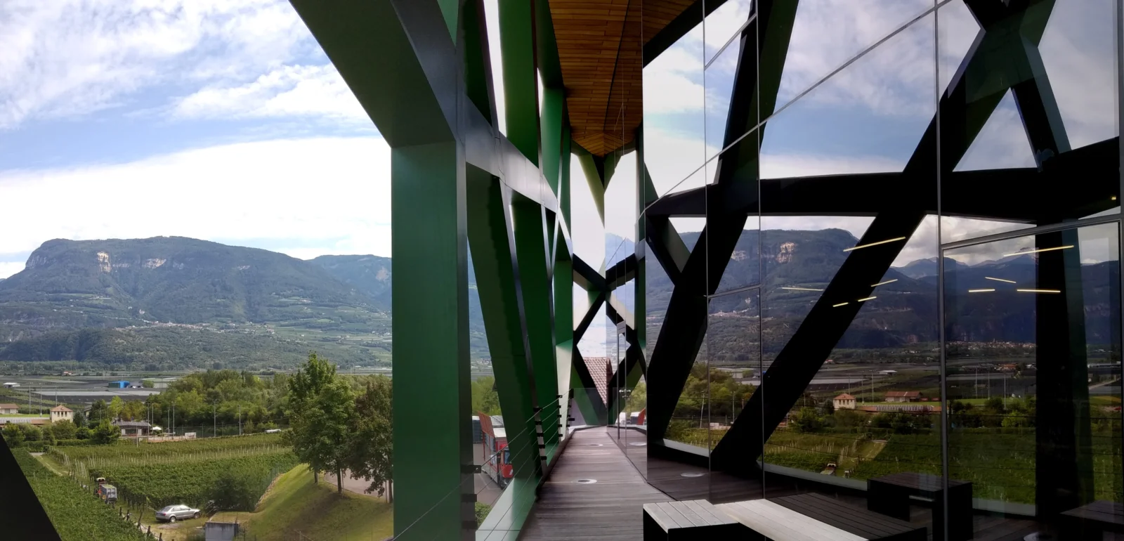 Il paesaggio riflesso nelle vetrate della Cantina Tramin accanto al reticolo verde, nel 2019