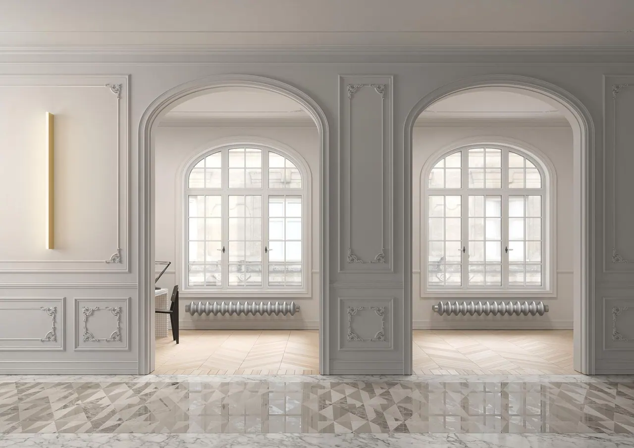 Radiatori Tubes MILANO/horizontal sotto due finestre ad arco in un interno con cornici decorative