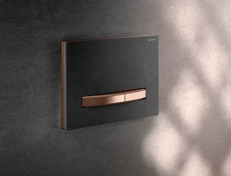 Placca Geberit Sigma50 con finitura Mustang e dettagli oro rosso