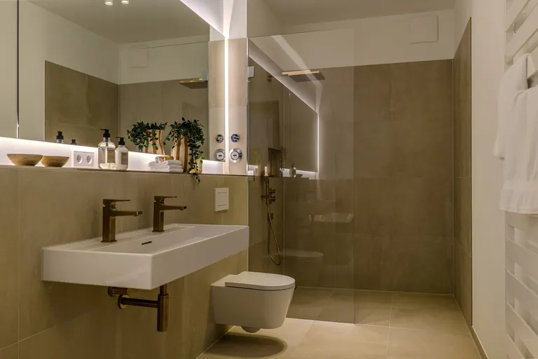 Il bagno della residenza di Amburgo con lavabo doppio, pietra chiara e rubinetti color bronzo