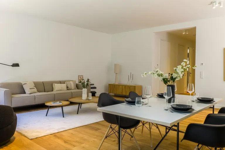 Soggiorno e zona pranzo con legno, tessuti chiari e sedie scure